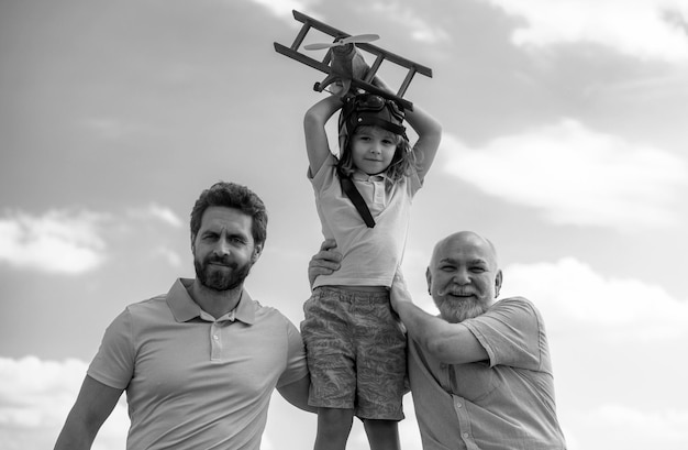 Foto tres generaciones diferentes de edades abuelo padre y hijo niño jugando con avión de juguete al aire libre