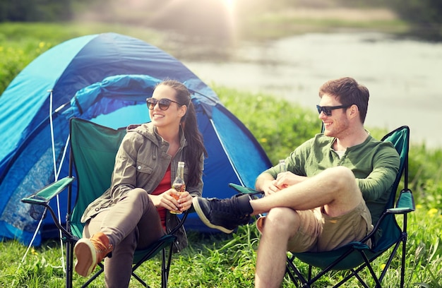 Foto um casal feliz a beber cerveja na tenda do acampamento.
