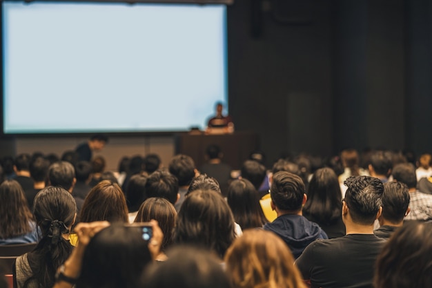 Foto vista trasera de la audiencia asiática que se une y escucha al orador hablando en el escenario del seminario