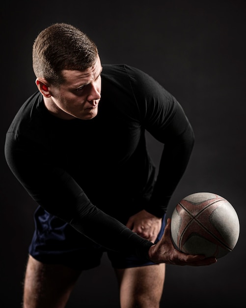 Vista frontal del jugador de rugby masculino guapo atlético sosteniendo la bola