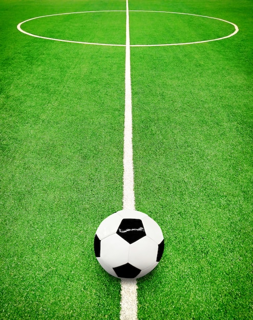 Vista en perspectiva del campo de fútbol verde con líneas blancas y balón de fútbol
