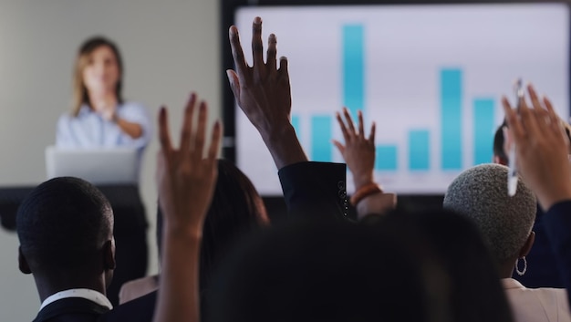 Abriendo la palabra para una sesión de control de calidad Vista trasera de un grupo de empresarios levantando la mano durante una conferencia en una oficina