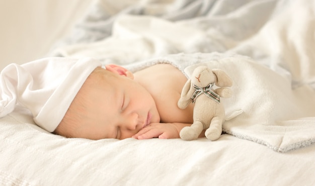 Adorable bebé recién nacido durmiendo en una habitación acogedora. Lindo retrato de bebé infantil feliz con cara de sueño en la cama