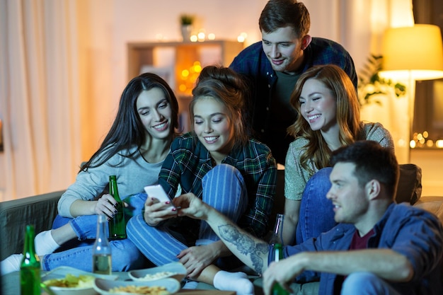 Foto amigos com smartphones a ver televisão em casa