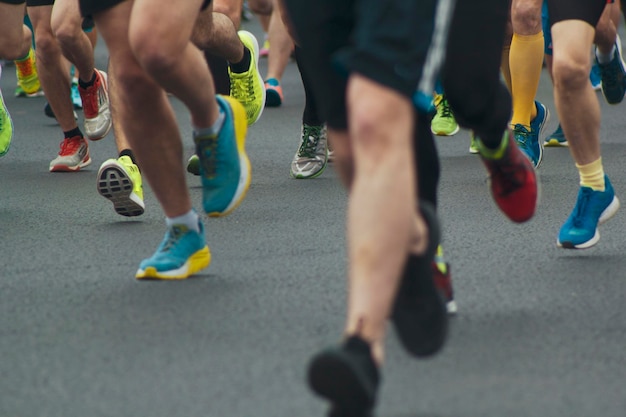 Foto atletas corredores corren por las calles de la multitud atletas piernas vista frontal