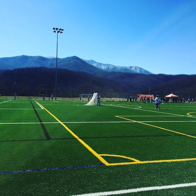 Foto campo de lacrosse contra las montañas en un día soleado