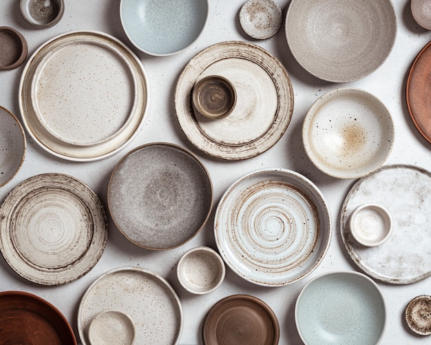 Cerámica hecha a mano, platos y cuencos de cerámica artesanales vacíos sobre fondo claro, vista superior