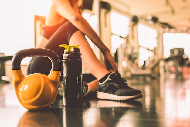 Foto cerrar kettlebells con entrenamiento de ejercicio de mujer en gimnasio gimnasio rompiendo relajarse después de deporte