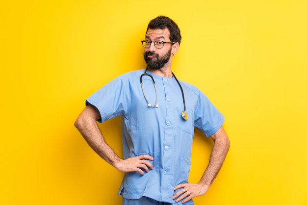 Foto cirurgião médico homem posando com os braços no quadril e rindo olhando para a frente