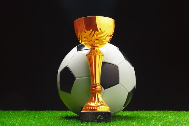 Foto copa de fútbol con pelota de fútbol sobre césped