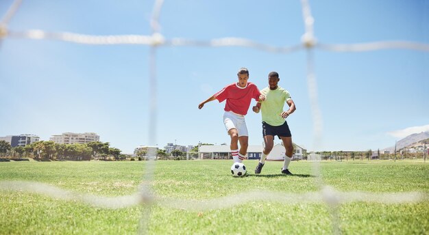 Foto deportes de fútbol y competencia con un atleta y un oponente jugando un juego en un campo de hierba aptitud y ejercicio de fútbol con un jugador de fútbol masculino y un rival corriendo en un campo para hacer ejercicio