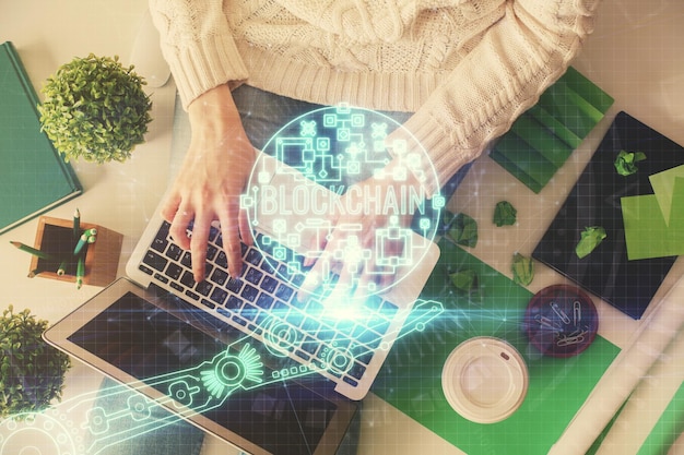 Foto doble exposición de manos de mujeres trabajando en computadora y dibujo holográfico de tema blockchain top view concepto de criptomoneda bitcoin