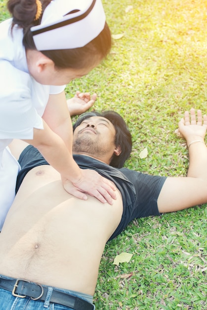 Foto doctor dando reanimación cardiopulmonar al hombre inconsciente en el parque de césped