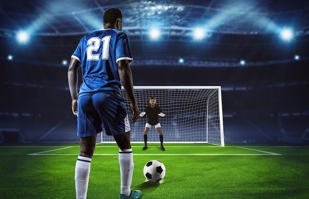 Escena de fútbol en el partido nocturno con jugador en uniforme azul pateando el penalti