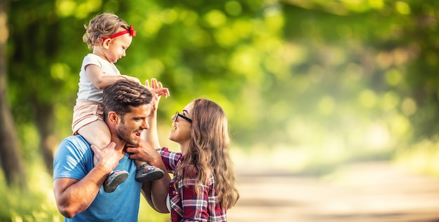 Foto familia feliz, padre, madre e hija están jugando en el parque y disfrutando de un día soleado de verano.