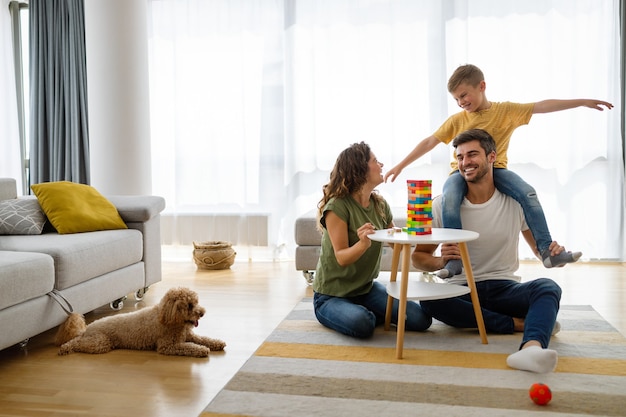 Foto familia joven feliz divirtiéndose, jugando juntos en casa con perro