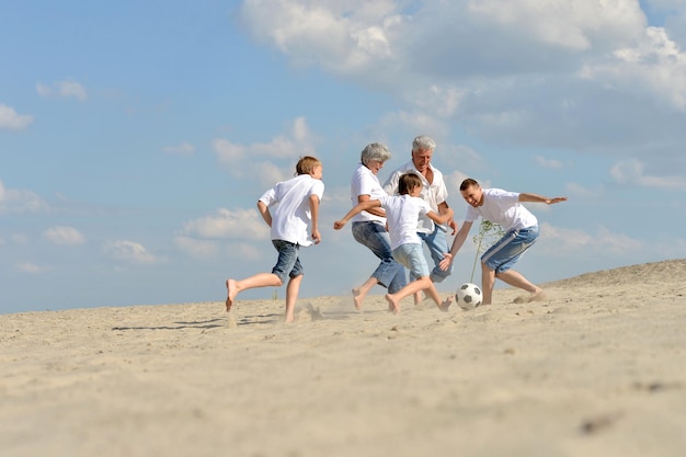 Familie spielt Fußball am Strand