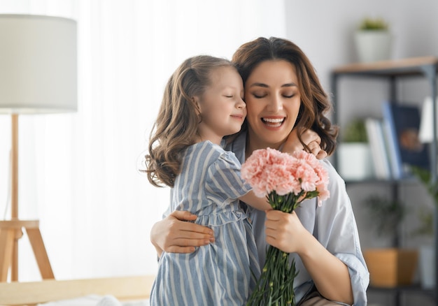 Foto feliz día la hija del niño felicita a la madre y le da flores mamá y niña sonriendo y abrazándose vacaciones familiares y unión