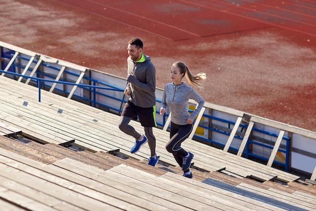 Foto fitness-, sport-, trainings- und lifestyle-konzept - paar läuft im stadion nach oben