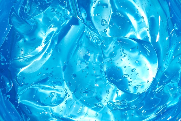 Fondo de textura de suero de gel cosmético o jalea de belleza. Telón de fondo de producto de colágeno azul transparente para el cuidado de la piel. Desinfectante antibacteriano o tóner de humedad de agua líquida manchado frotis de cerca
