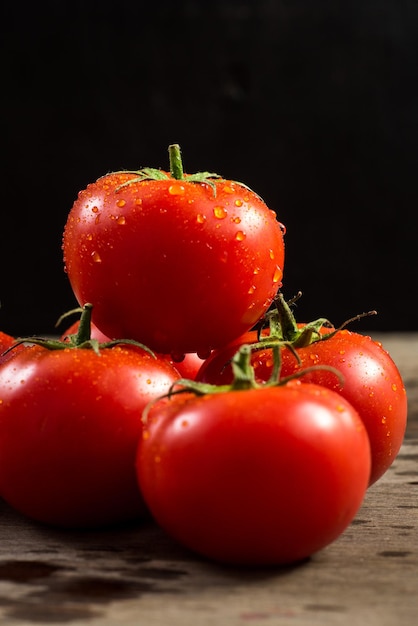 Frische rote Tomaten mit Wassertropfen auf Holzhintergrund