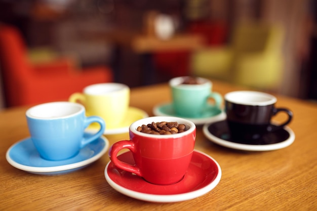 Granos de café en bolsa y cuchara con taza de café roja sobre mesa de madera blackground borroso