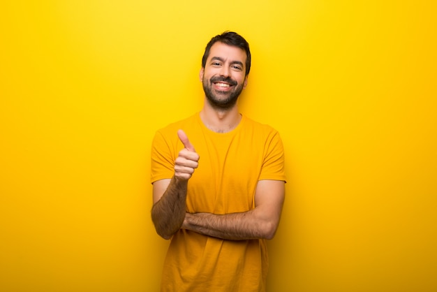 Foto hombre en color amarillo vibrante aislado que da un gesto con los pulgares arriba porque algo bueno ha sucedido