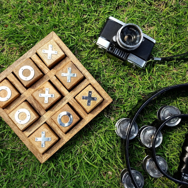 Foto hochwinkelansicht der kamera mit tic-tac-toe und tamburin auf einem grasfeld