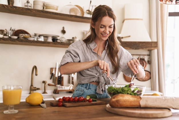 Foto imagem de jovem satisfeito feliz concentrado linda mulher bonita dentro de casa na cozinha cozinhando.