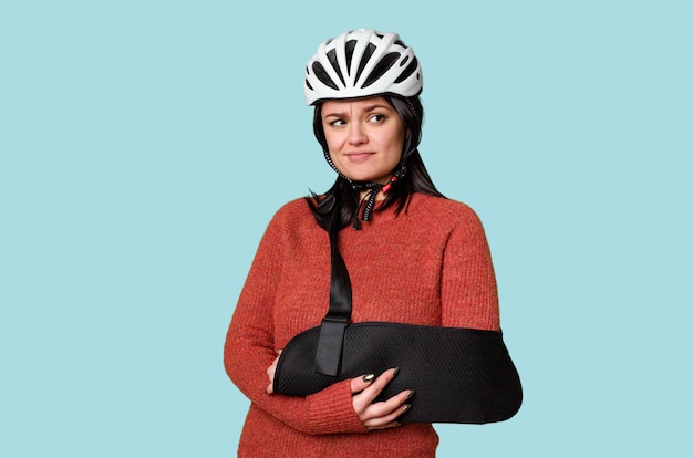 Jovem ciclista com lesão na estrada usando tipoia mostra desconforto ou expressão de dor