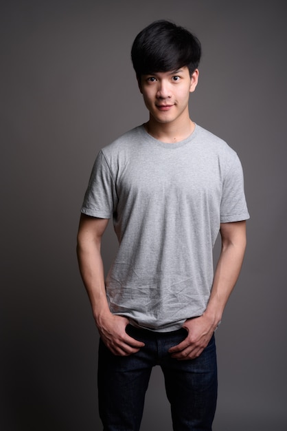 Foto joven apuesto hombre asiático contra la pared gris