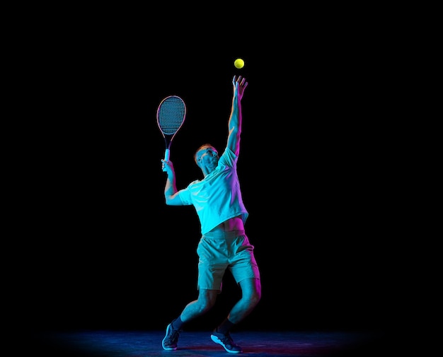 Foto joven deportista profesional tenista en acción de movimiento aislado sobre fondo oscuro en