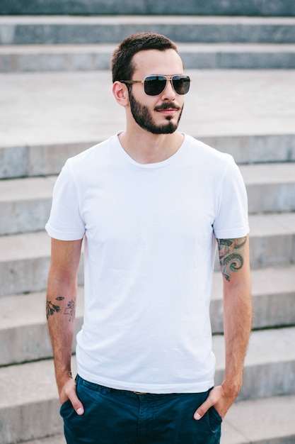 Foto un joven elegante con barba en una camiseta blanca y gafas