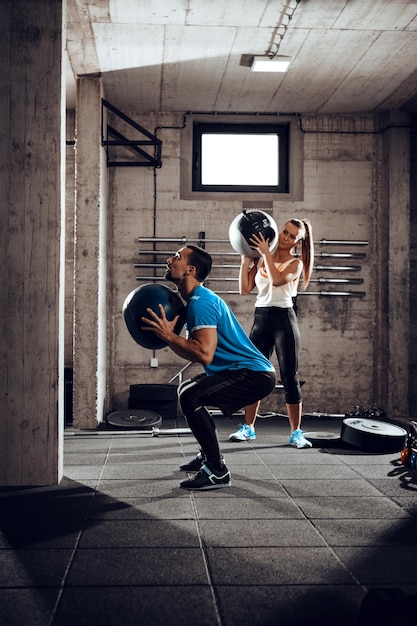 Foto joven pareja musculosa haciendo ejercicio juntos en el gimnasio.