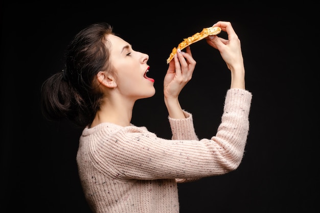 Junge kaukasische Frau mit Heck Stück Pizza essend.
