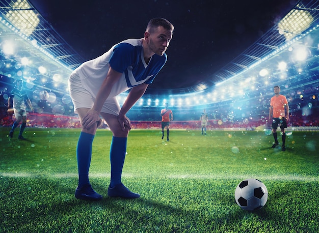 Jugador de fútbol listo para patear el balón de fútbol en el estadio iluminado durante el partido