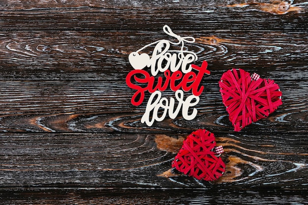 Foto konzept für den valentinstag. inschrift „liebe, süße liebe“. rote gewebte herzen der liebe