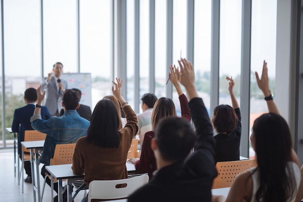 Foto levantó las manos y los brazos de un grupo grande en la sala de clase del seminario para ponerse de acuerdo con el orador en la sala de reuniones del seminario de la conferencia