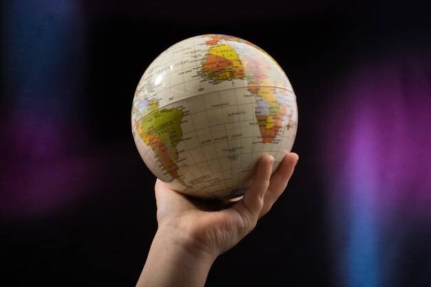 Foto mano sosteniendo un globo terráqueo con el mapa en él