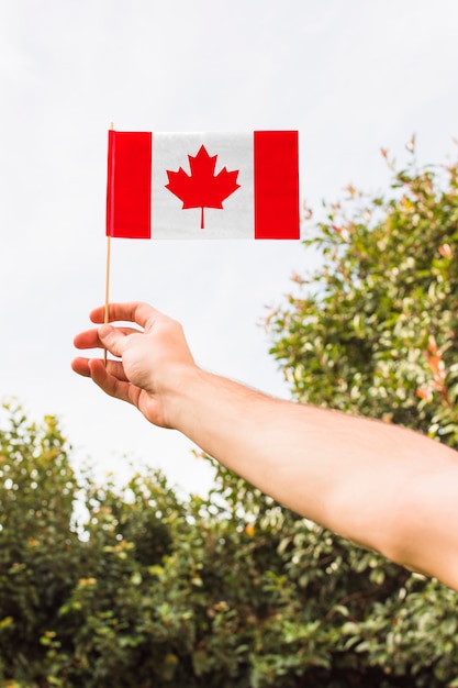 Foto mão segurando a bandeira canadense ao ar livre