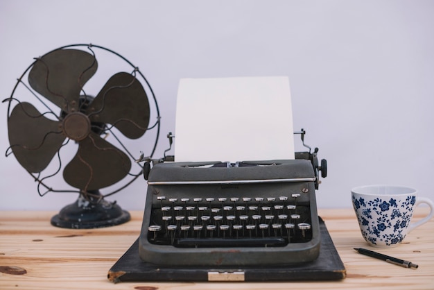 Máquina de escribir entre taza y ventilador