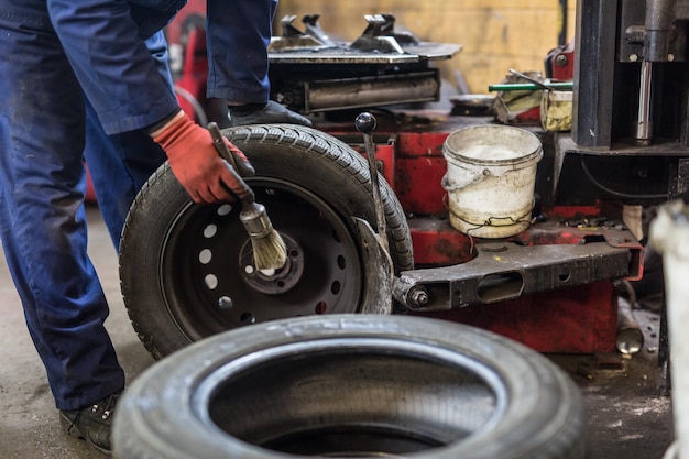 Mecánico de automóviles profesional que reemplaza el neumático en la rueda en el servicio de reparación de automóviles