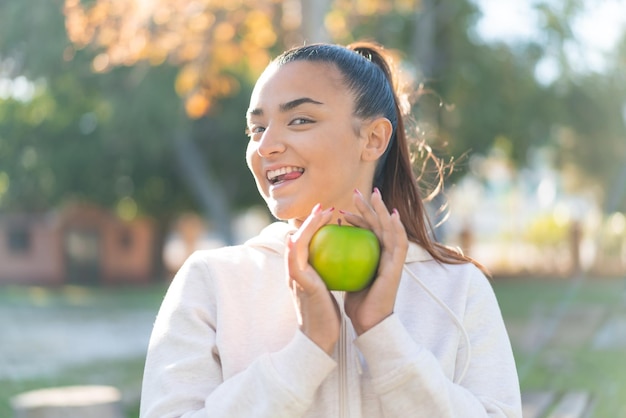 Foto mujer bonita joven del deporte que sostiene una manzana con expresión feliz