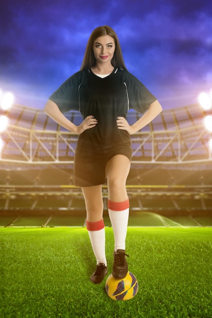 Foto mujer futbolista con balón de fútbol en el estadio