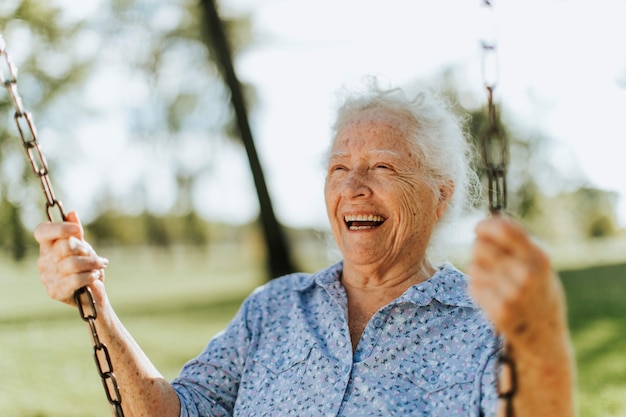 Foto mujer senior alegre en un columpio en un patio de recreo
