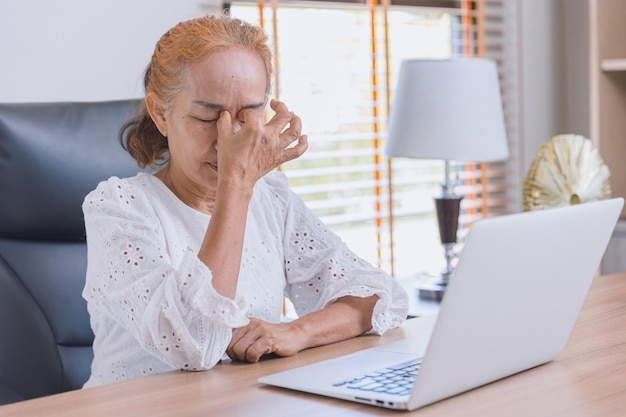 Mulher idosa com dor nos olhos da astenopia estresse sinusite cansado sofre fadiga do trabalho duro com a tela do computador