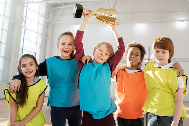 Foto niños felices de tiro medio con copa dorada.