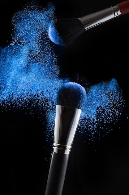 Foto professionelle pinsel und blaues pulver auf schwarzem hintergrund make-up-kosmetik