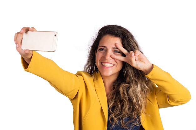 Foto retrato de uma jovem mulher bonita tomando uma selfie com seu telefone celular isolado em um estúdio.