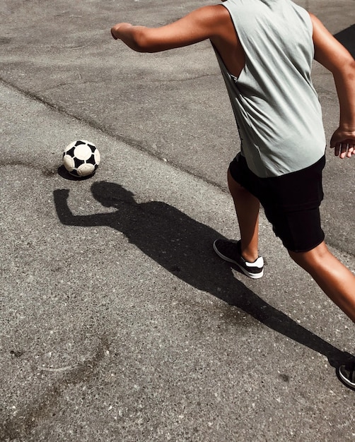 Foto sección baja de un hombre jugando al fútbol en la calle